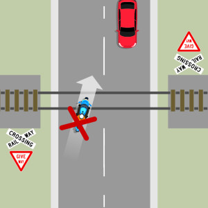 A blue motorcycle is crossing railway lines at a 45 degree angle. A red x shows this is the wrong thing to do.