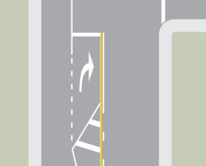 In the middle of a laned road, a white triangle is painted with diagonal lines inside it, followed by an arrow pointing right.