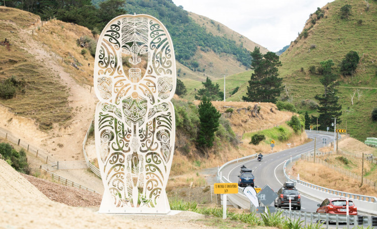 white sculpture sitting on hill near motorway